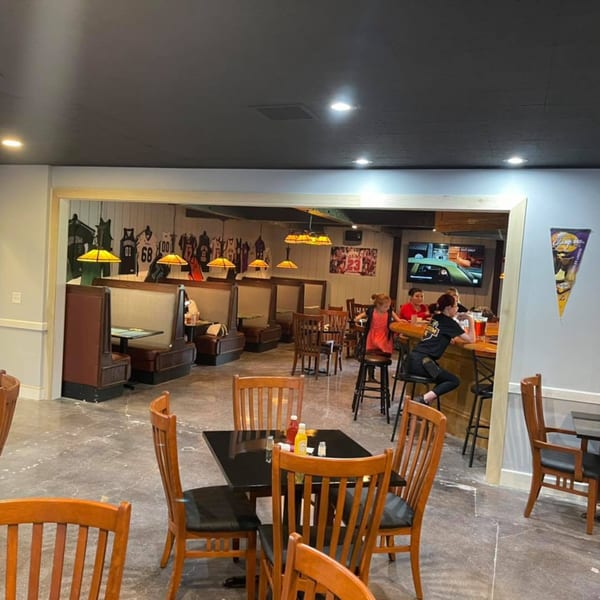 Interior of Stadium 34 showing dining tables, booths, a bar with patrons, and sports jerseys on the wall.