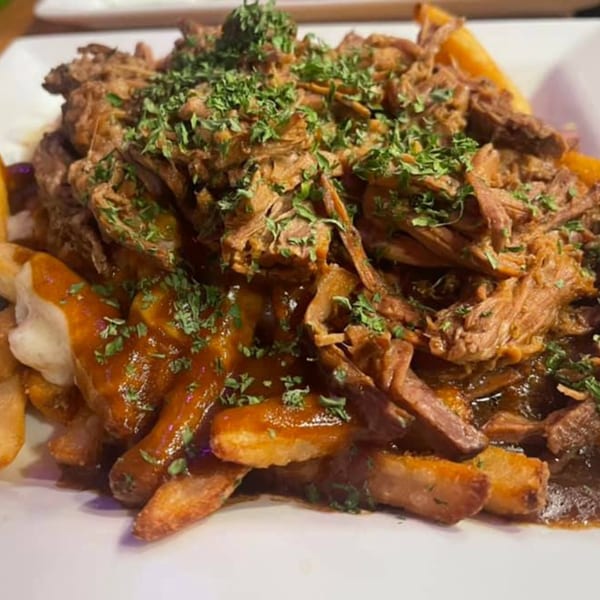 Close-up of Stadium 34's poutine with fries, gravy, cheese curds, shredded beef, and parsley.