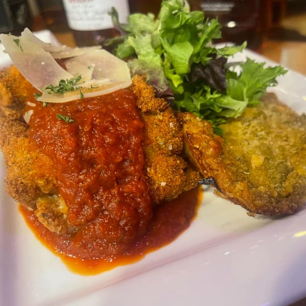 Crispy fried chicken cutlets topped with marinara sauce, shaved parmesan, and a side salad.