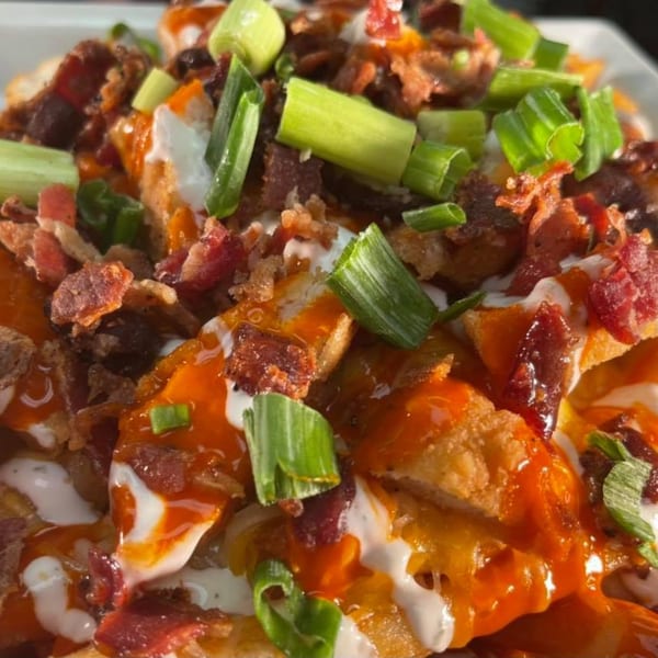 Close-up of Stadium 34's loaded fries with bacon, green onions, and various sauces.