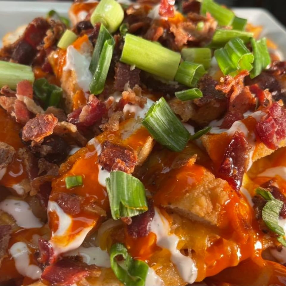 Close-up of Stadium 34's loaded fries with bacon, green onions, and various sauces.
